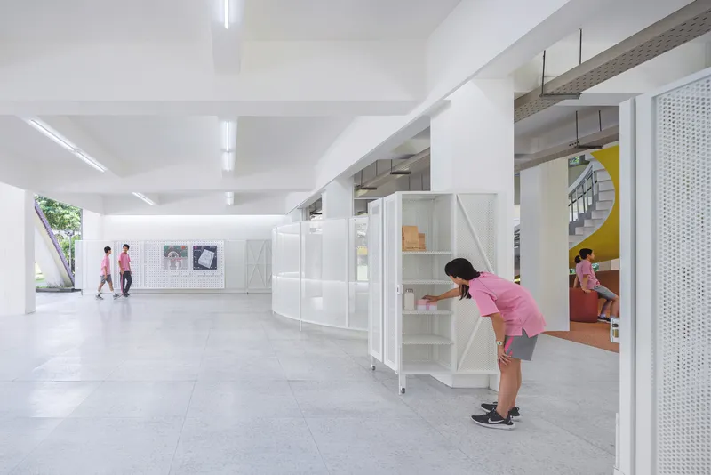 White modular storage units on wheels with perforated metal panels in a column-filled interior