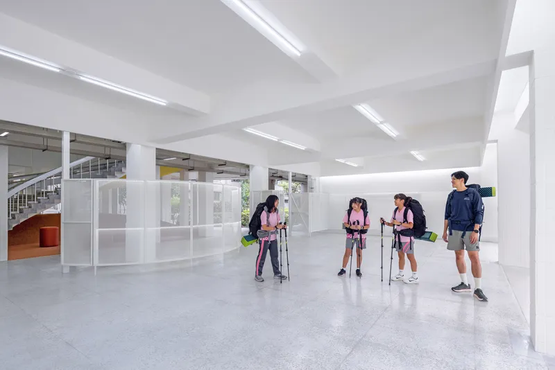 Entry space with exposed concrete ceiling beams and students preparing hiking gear on the floor