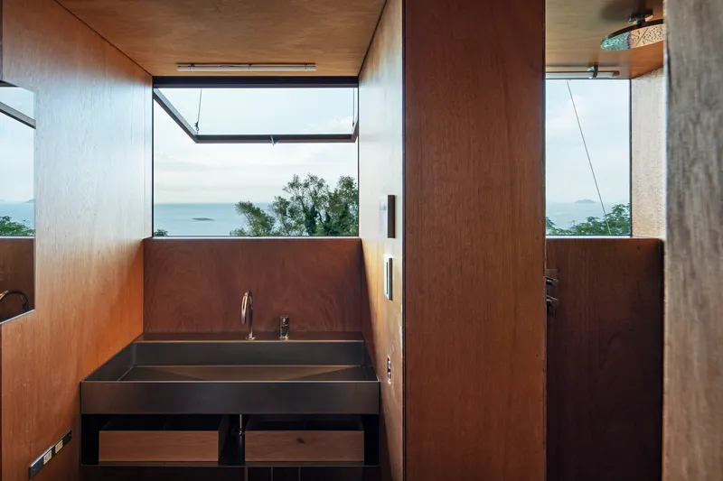 Dark metal sink beneath a clerestory window framing distant islands and trees