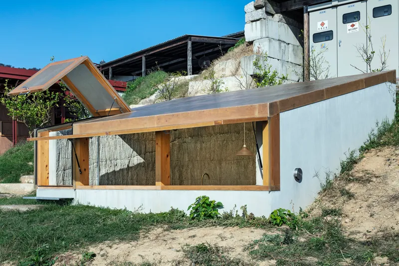 Close-up of timber frame structure with board-formed concrete wall and white stucco base