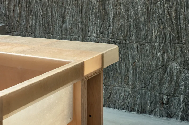 Detail of plywood countertop edge against rough-textured vertical concrete block wall