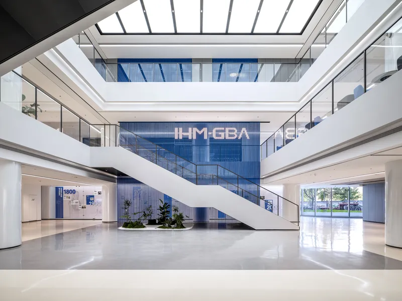 Multilevel atrium with diagonal white staircase and skylight above polished stone floor
