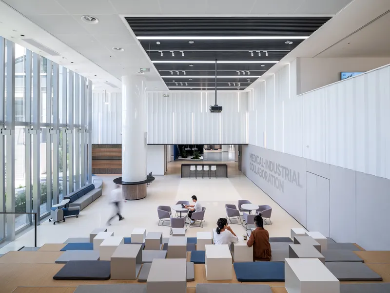 Double-height gathering space with modular floor cushions and suspended projection screen