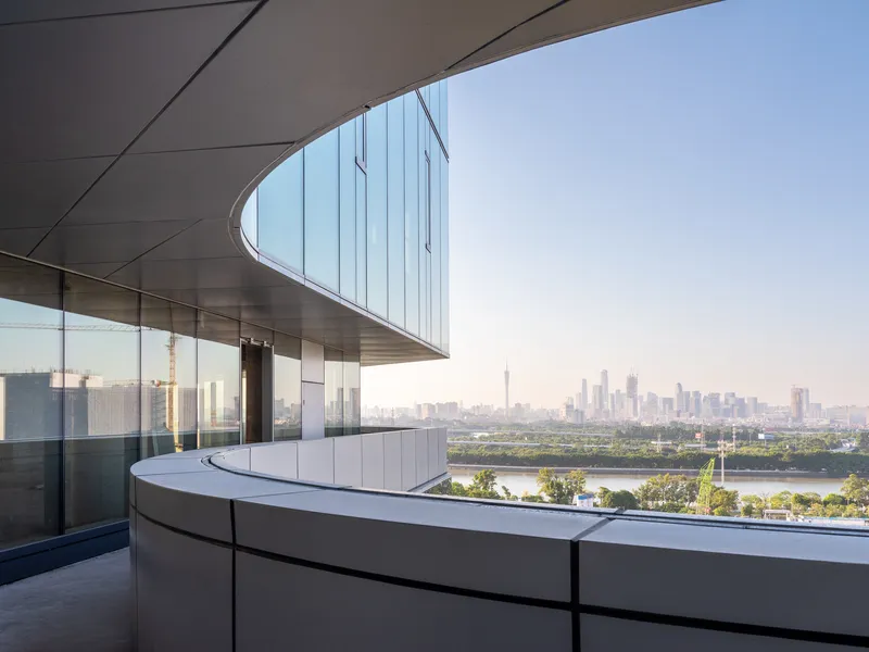 Curved canopy overhanging a white paneled terrace with distant cityscape and river visible beyond
