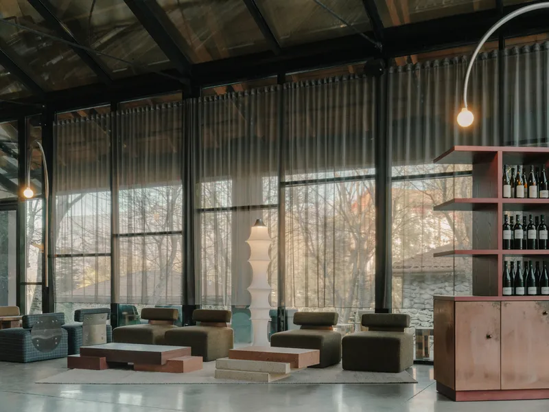 Lounge area with steel-framed glazing, sheer curtains and view to bare trees outside