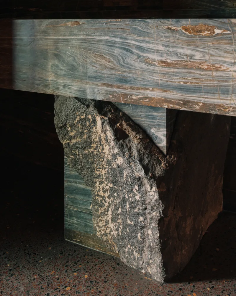 Close-up of marbled stone bench with rough quarried block base on terrazzo flooring