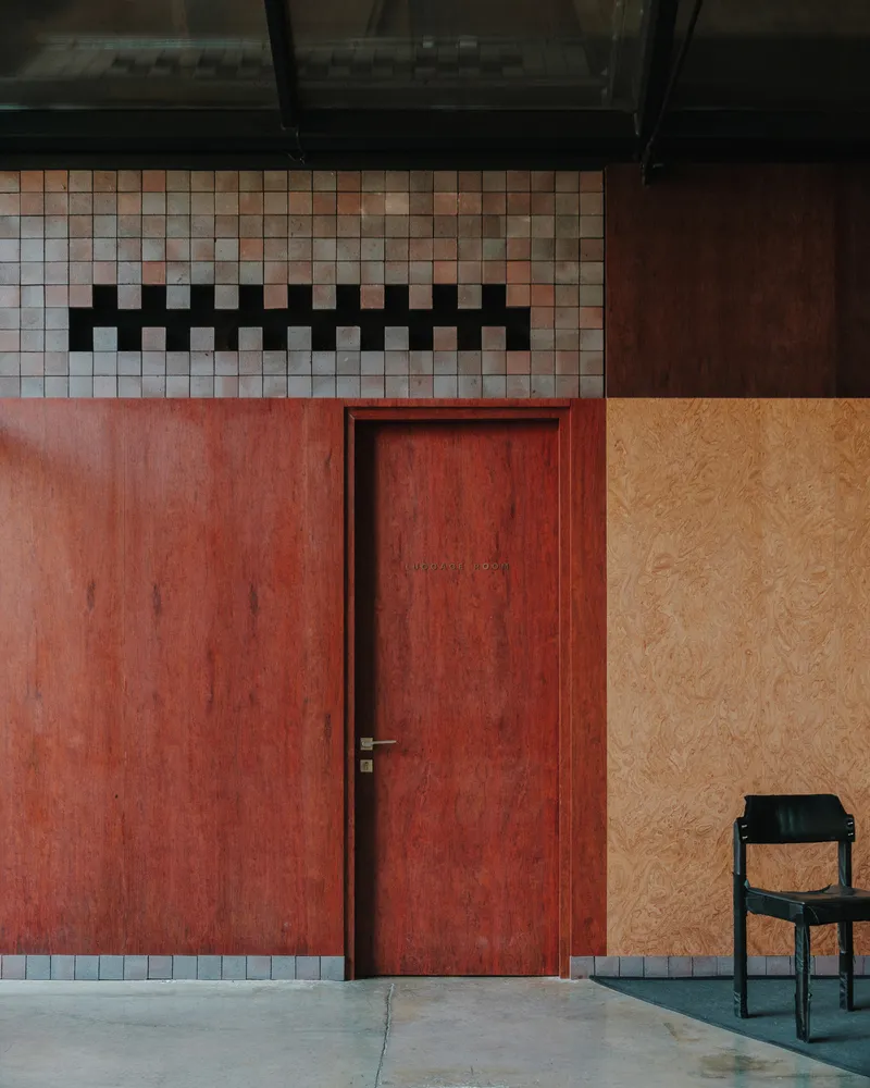 Red plywood door with mosaic tile clerestory band and adjacent plywood wall panel