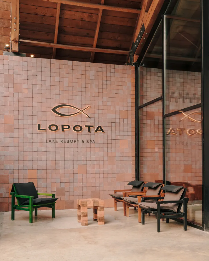 Tiled feature wall with branding beneath exposed timber rafters and glazed facade