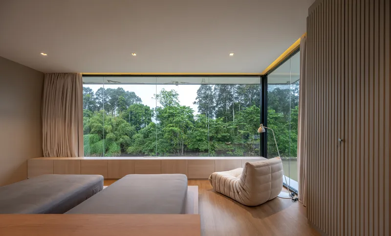 Interior lounge with floor-to-ceiling glazing overlooking the forested landscape at dusk