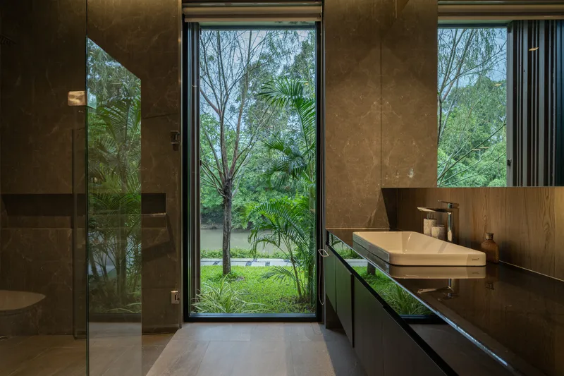 Bathroom interior with full-height glazing framing palm trees and garden beyond