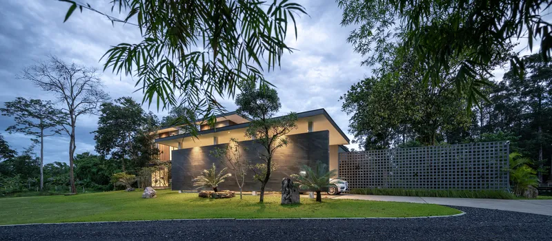 Entrance facade with perforated screen wall and gabled rooflines illuminated at dusk