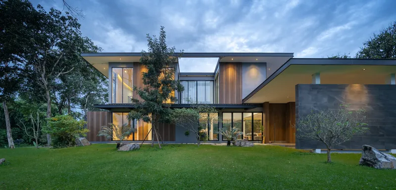 Garden elevation showing staggered volumes with cantilevered roofs and glazed connections at twilight