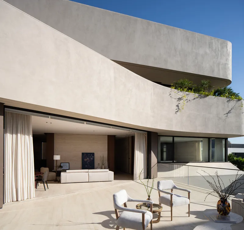 Cantilevered upper terrace with planted edge above open living room with floor-to-ceiling glazing and seating