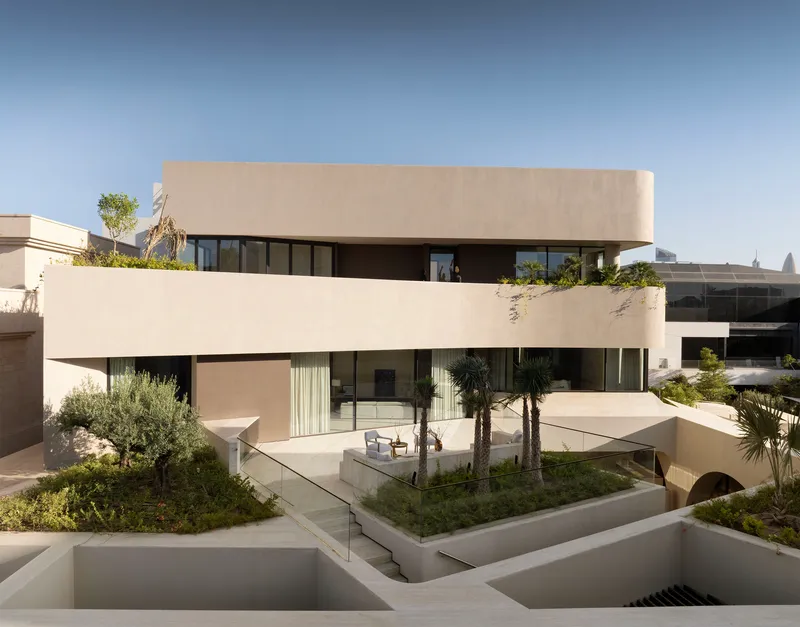 Garden view of the tiered facade with terraces, olive trees, and sunken planters in morning light