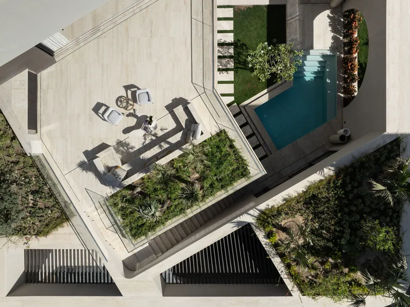 Aerial view of terraced courtyards with pool and outdoor furniture casting long shadows