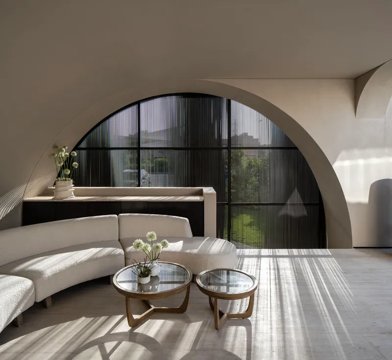 Interior living room with arched black-framed window casting striped shadows across the polished floor