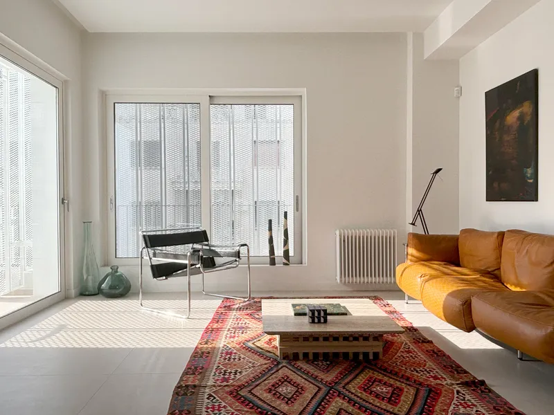 Living room with white radiator, patterned rug, and sliding doors with perforated metal screens filtering daylight