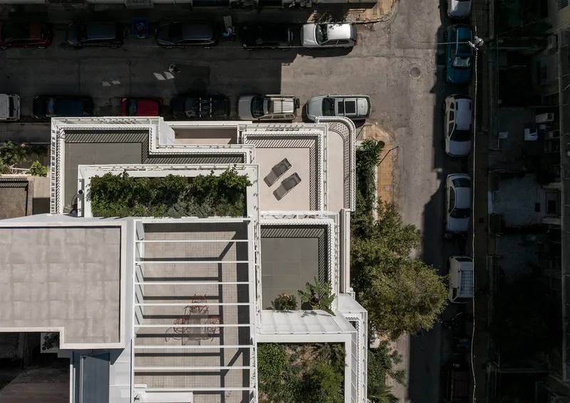 Drone view of the staggered rooftop terraces with planted beds and furniture overlooking parked cars