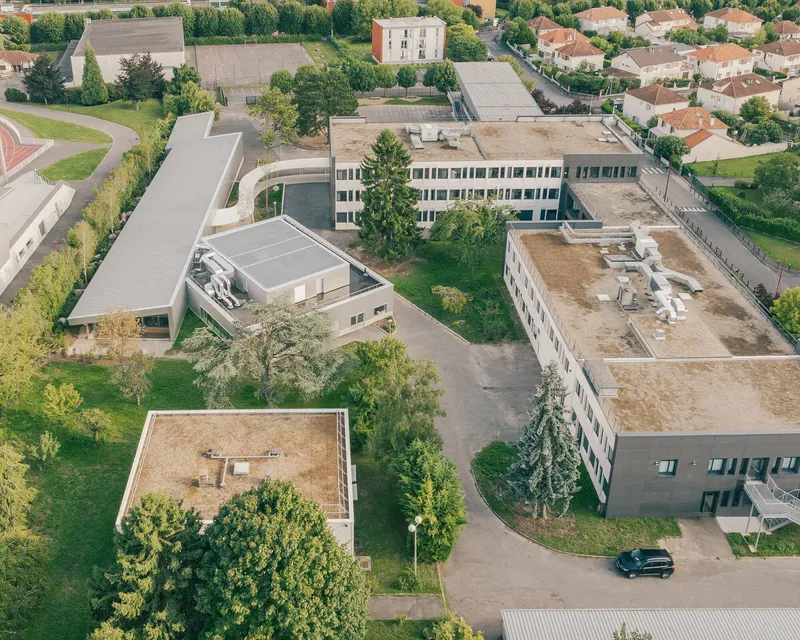 Drone view of school campus with flat roofs and courtyards surrounded by residential neighborhood