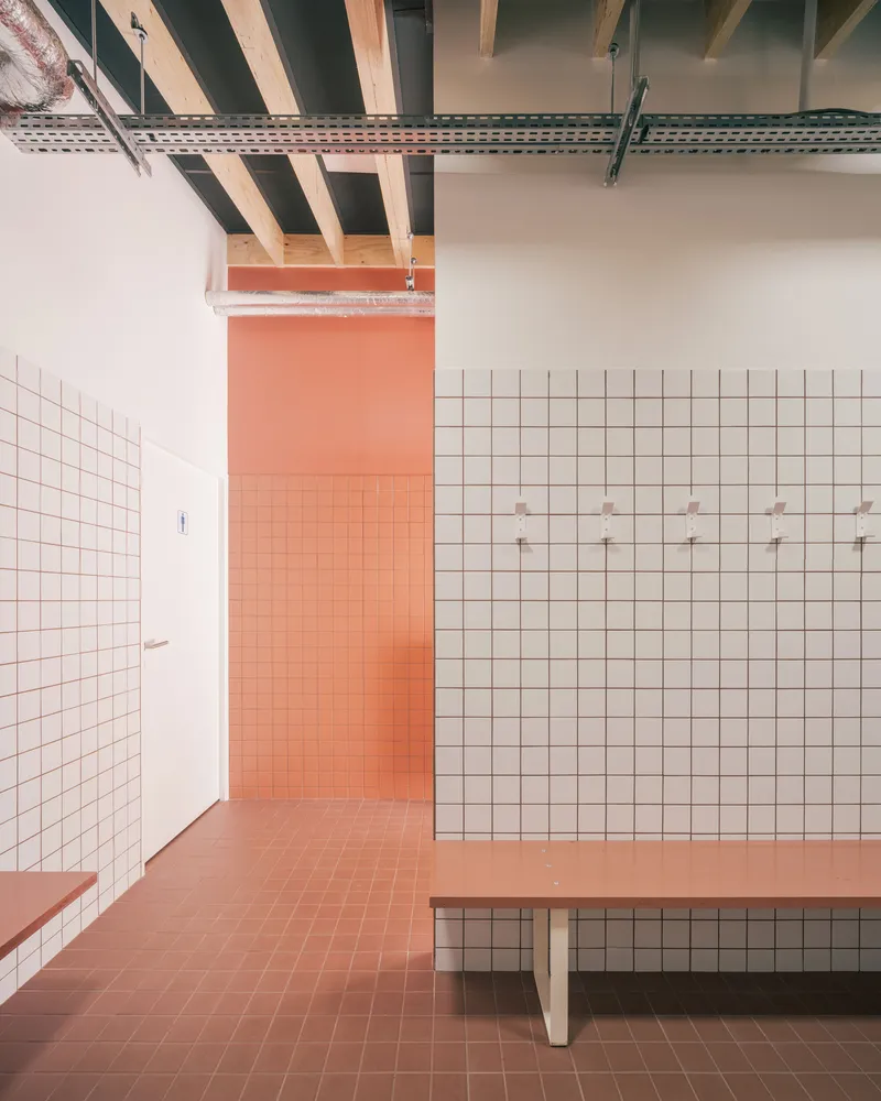 Corridor with terracotta floor tiles and white gridded wall tiles beneath exposed timber joists