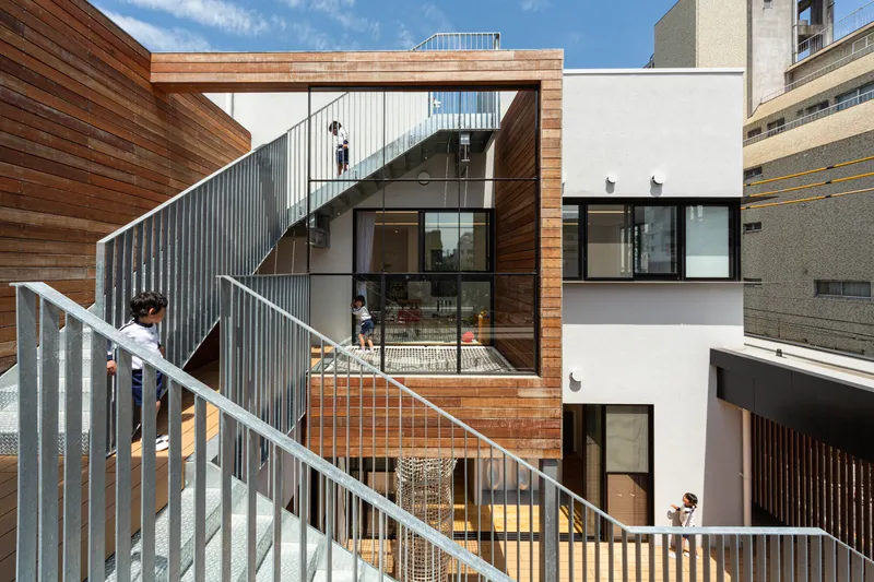 Exterior staircase with corrugated metal screen connecting multiple levels with children walking
