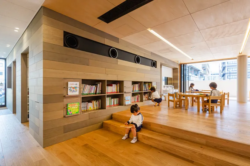 Interior library area with built-in bookshelves and children seated at timber tables