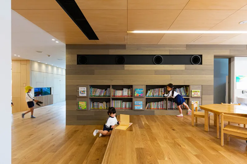 Interior space with wood flooring, built-in bookshelves and children using the reading area