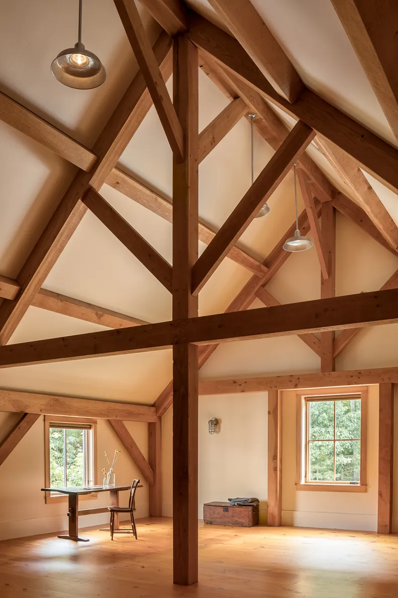 Interior view of exposed timber frame structure with king post trusses and pendant lights