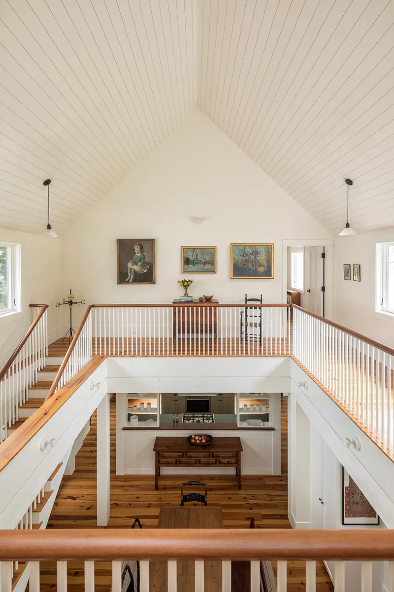 Upper gallery overlooking entry hall with paired staircases and tongue-and-groove vaulted ceiling