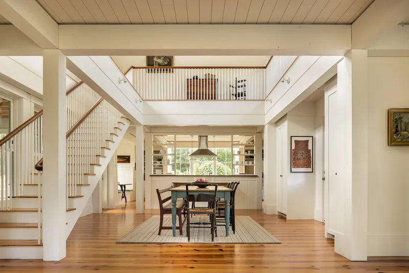 Double-height dining space with wood floors, open stair and mezzanine overlooking the kitchen