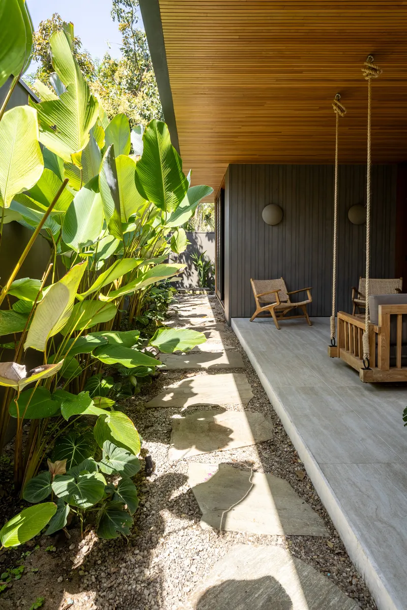 Narrow garden pathway with stepping stones and banana plants alongside the timber-clad wall
