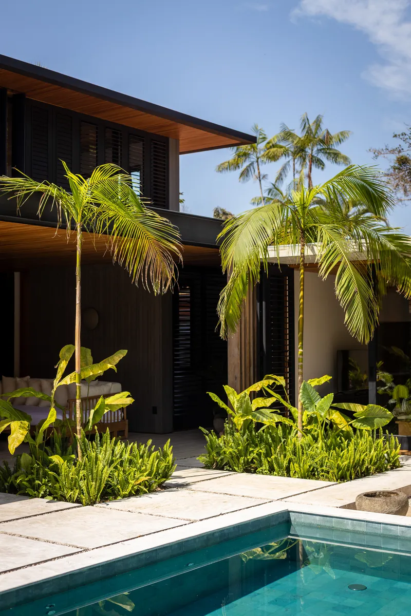 Pool courtyard framed by palms and planted beds under afternoon sunlight