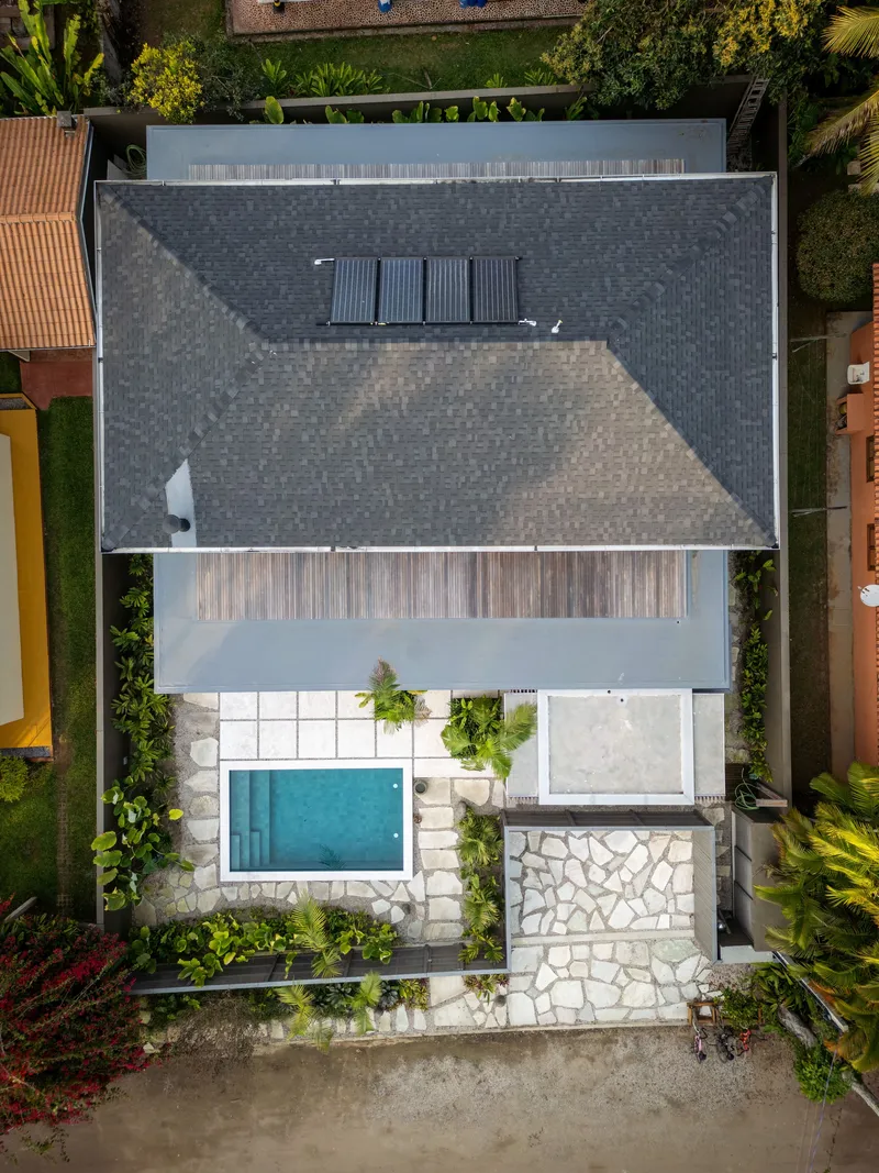 Aerial view of the dark tiled roof with solar panels and the pool courtyard below