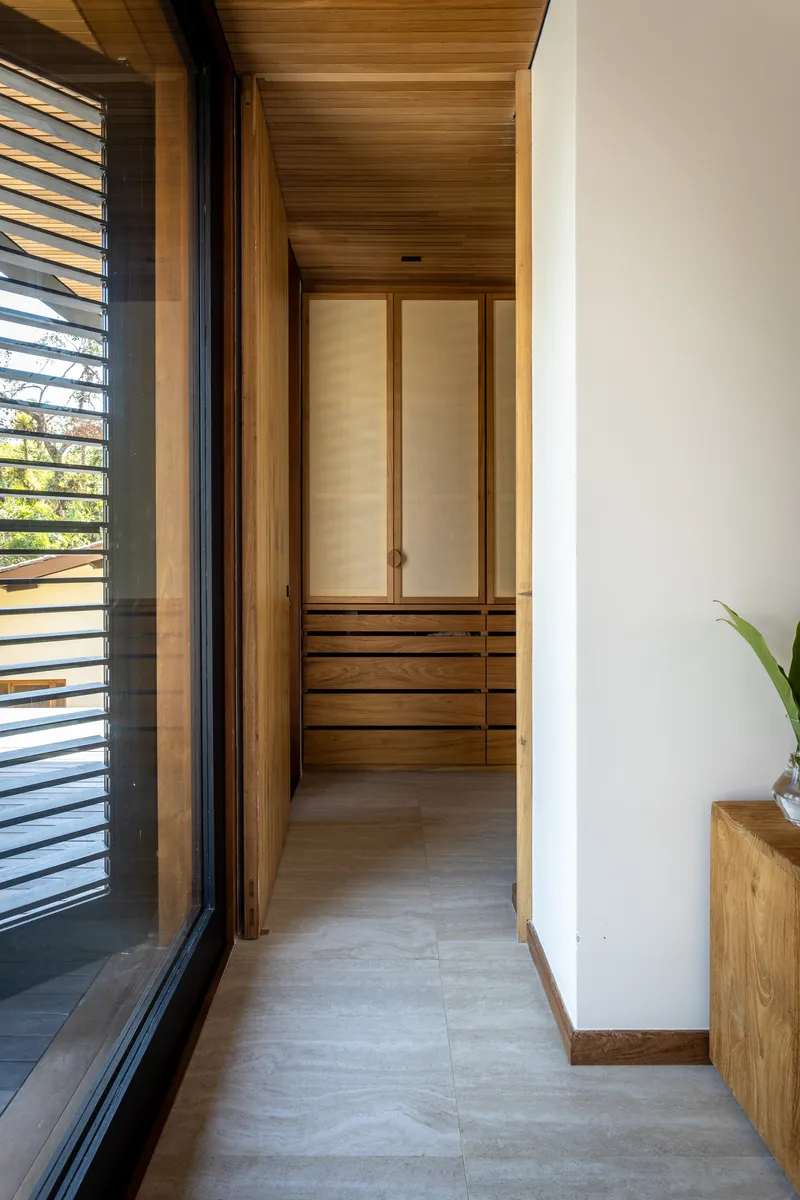 Narrow corridor with timber ceiling and built-in wardrobe with louvered sliding doors at the end