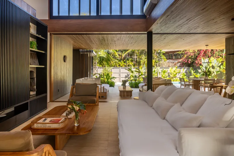 Open living area with ribbed timber ceiling and clerestory windows overlooking a tropical garden