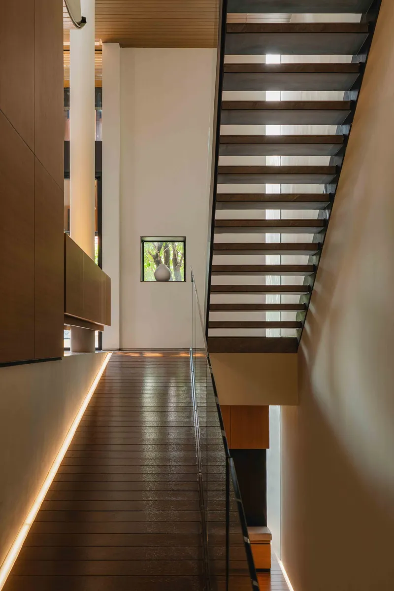 Open timber tread staircase with glass balustrade and suspended wood millwork alongside the landing