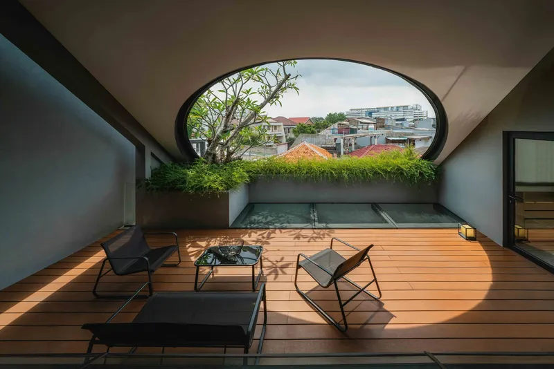 Rooftop terrace with timber deck, shallow lap pool and arched opening framing view of neighboring buildings