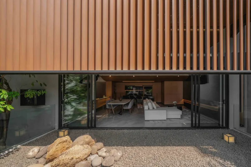 Courtyard view through folding glass doors to the living space beneath a vertical timber slat overhang