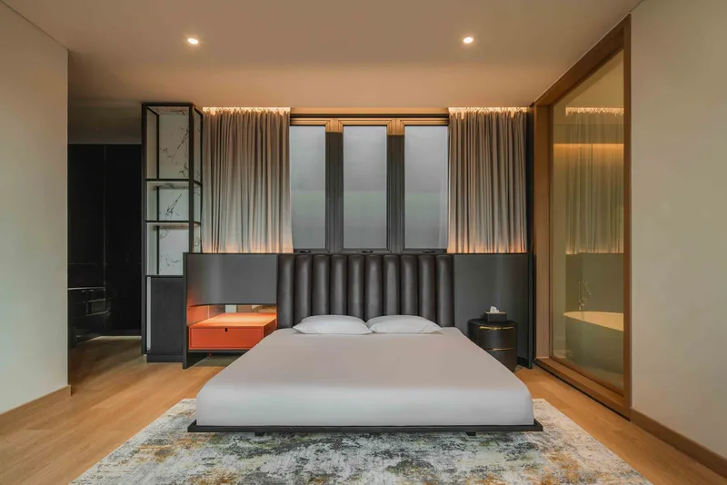 Bedroom interior with channeled leather headboard, translucent curtains and backlit panels flanking the bed