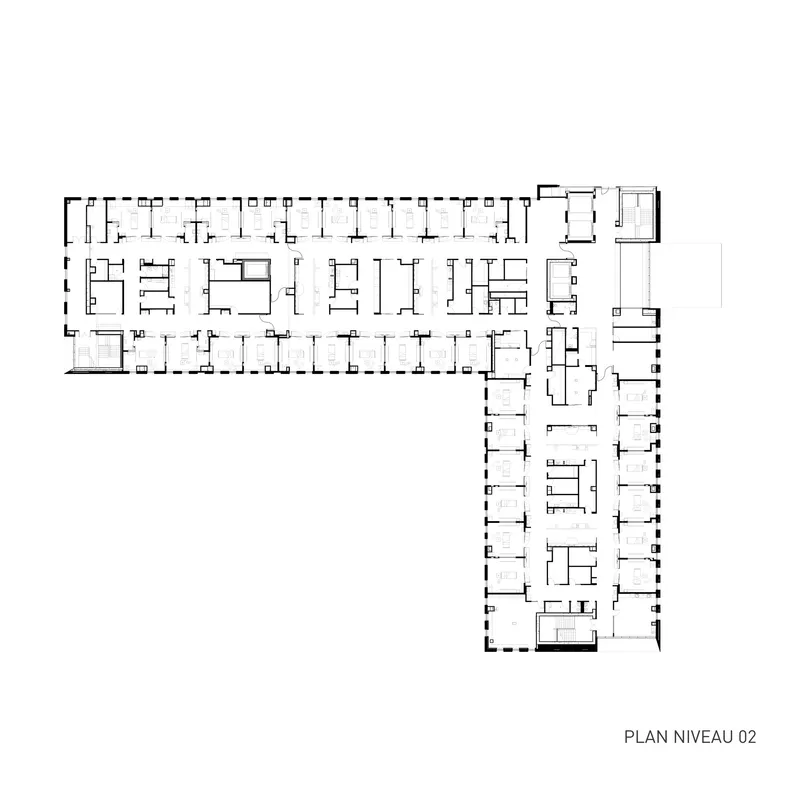 Floor plan drawing showing L-shaped layout with repeated cellular rooms along perimeter corridors