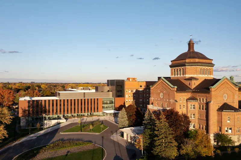 Aerial view of the campus complex with historic brick buildings and new volumes in autumn light