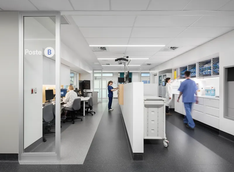 Interior workstation corridor with white casework and medical staff in motion under suspended tile ceilings