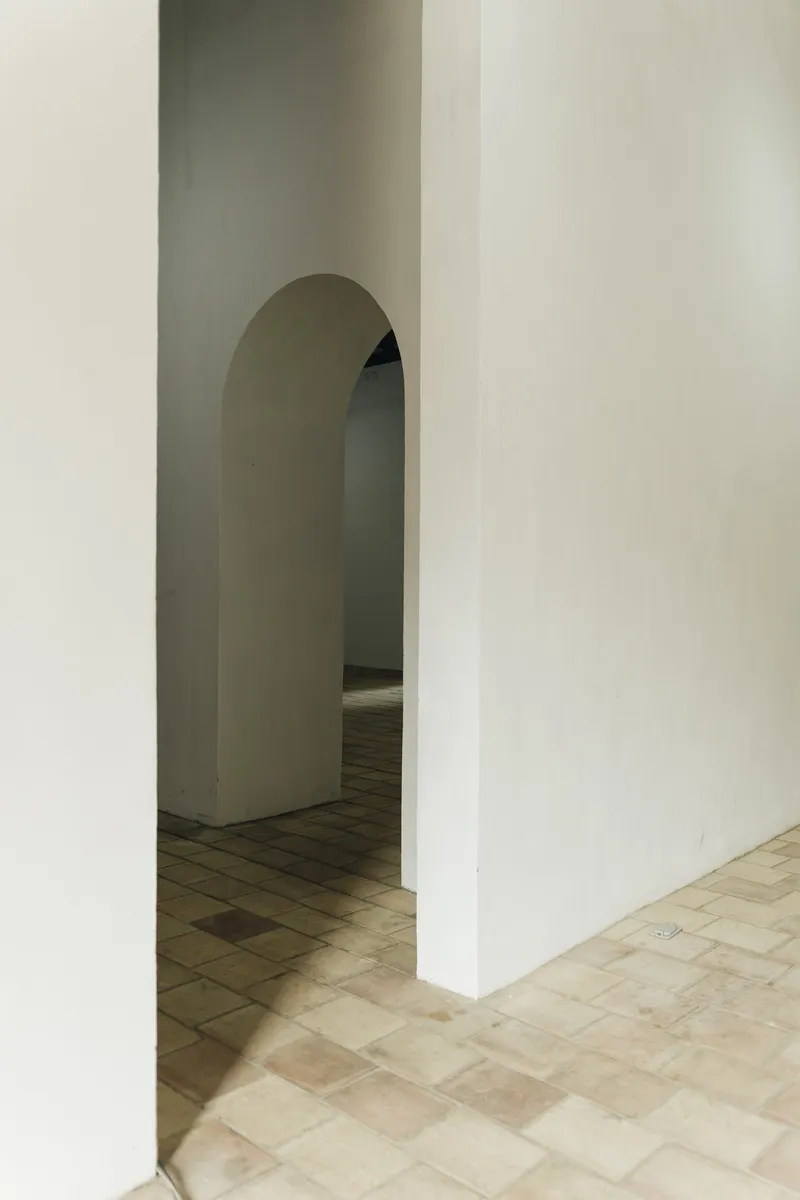 Sequence of arched doorways through white plastered walls with terracotta floor tiles