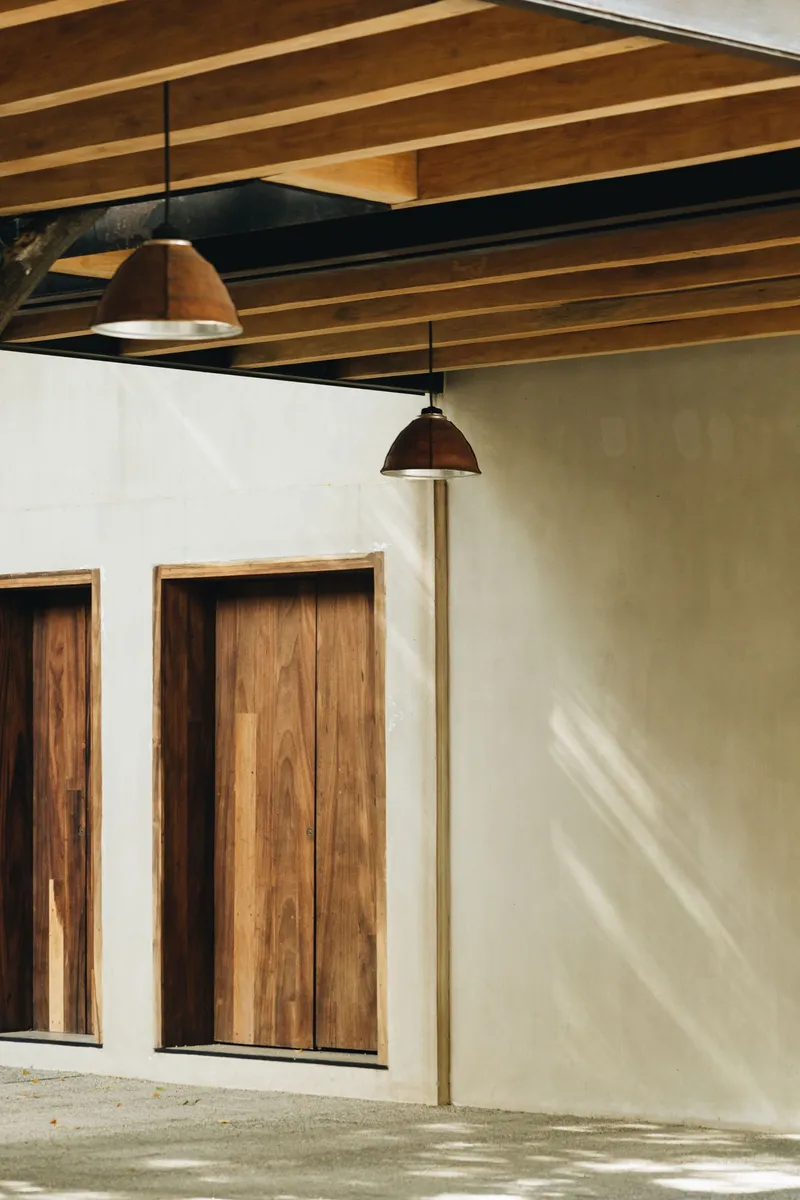 Interior courtyard with exposed timber beams and pendant lights casting afternoon shadows