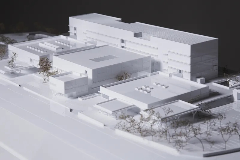 Physical model showing white massing with flat roofs, internal courtyards and miniature trees