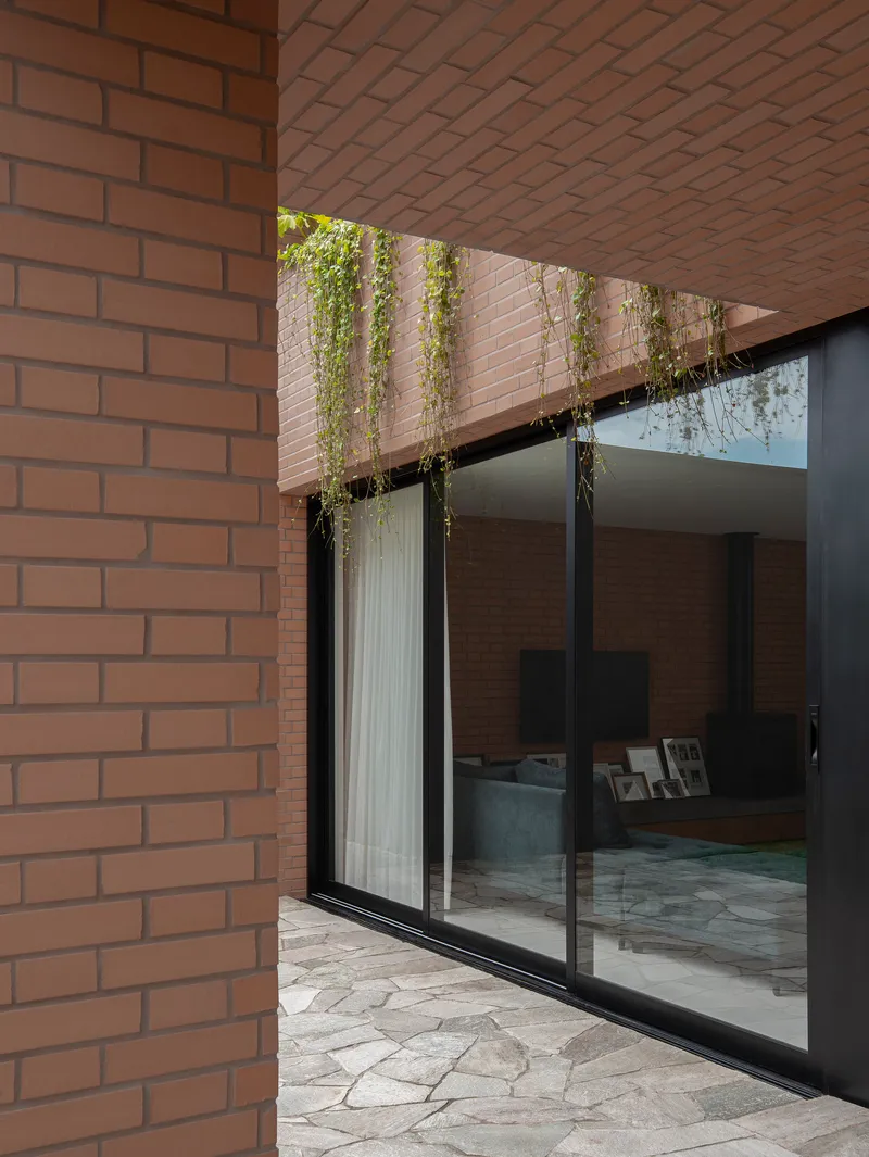 Sliding glass door opening to courtyard beneath a planted balcony with trailing greenery
