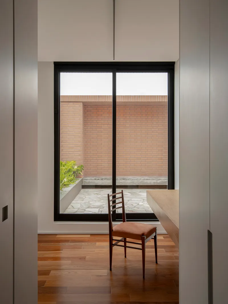 Interior workspace with timber desk and single chair framed by white walls and black window