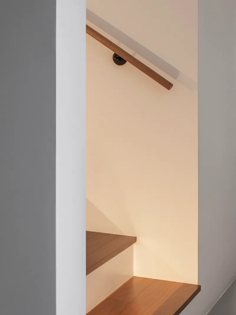 Detail of timber handrail meeting wall bracket beneath warm ambient lighting