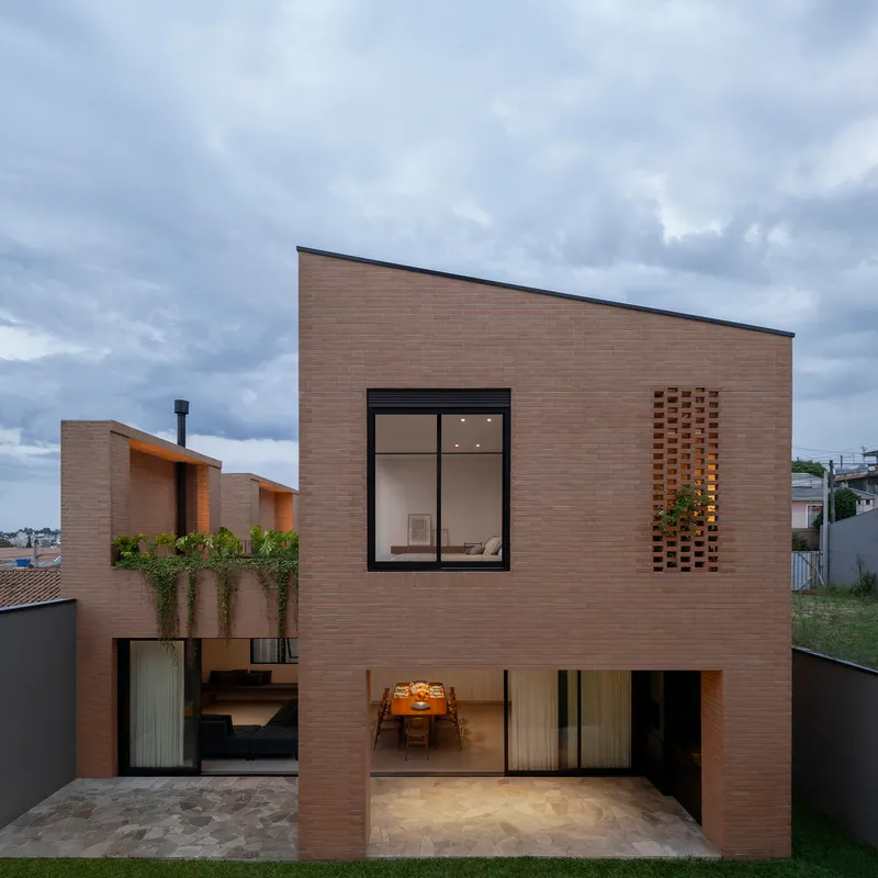 Street elevation of brick volume with perforated wall panel under overcast sky