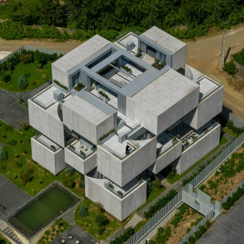 Aerial view of the interlocking concrete volumes with multiple roof terraces and central courtyard opening